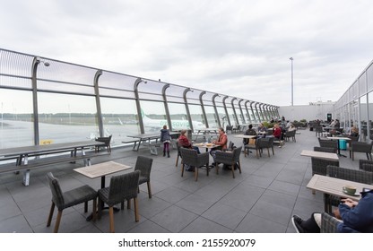 Eindhoven, Netherlands 5 May 2022 : People sitting at table outside Eindhoven airport at viewing deck overlooking tarmac and airplanes 