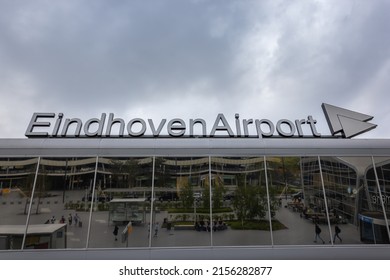 Eindhoven, Netherlands 5 May 2022 : Eindhoven Airport Sign On Top Of Terminal Building And Reflection Of Tourists Walking And Sitting In The Glass Window 
