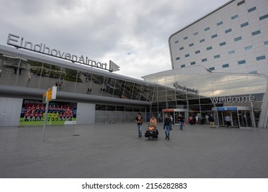 Eindhoven, Netherlands 5 May 2022 : Family of tourist passengers with trolley and suitcases outside Eindhoven airport. Child sitting on bags and man holding baby 
