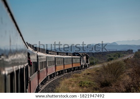 El Chepe, last passenger train in Mexico ascends Sierra Madre, Tarahumara mountains in the northern state of Chihuahua. A tourist admires the views of a desertic landscape with morning sunlight.
