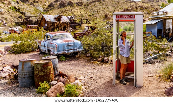 El\
Dorado Canyon, Nevada/USA - June 10 2019: Vintage phone booth and\
vintage cars used in movies on display in the old mining town of El\
Dorado in the Eldorado Canyon in the Nevada\
Desert