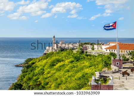 El Morro Spanish fortress with lighthouse, cannons and Cuban flag in th foreground, with sea in the background, Havana, Cuba