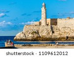 El Morro spanish fortress walls with lighthouse, walking people and fishermen in the foreground, Havana, Cuba