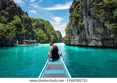 El Nido, Palawan, Philippines, traveler sitting on boat deck exploring the natural sights around El Nido on a sunny day.