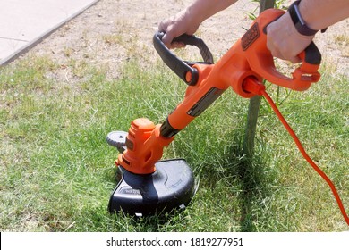 El Paso, Texas / USA: Circa September 2020

Trimming the grass with an electric weed wacker  
Cutting weeds with an electric trimmer.