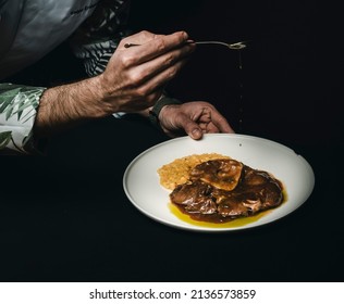 An Elaborate Meal Presentation Of A Thick-cut Round Steak. After The Meat Is Cooked, It Becomes Flat, Very Tasty And Served With Risotto. The Chef Pours Various Sauces On This Dish.