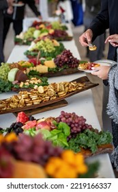 Elaborate Outdoor Event Food Table With People Choosing Snacks