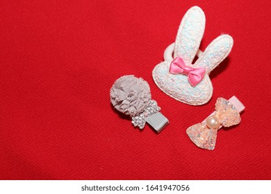 Elastics And Stilettos On A Red Background. Baby Hair Ornaments. Girl Accessories Near The Casket. Hairpins, Earrings, Rings Are The Treasures Of A Little Girl. Baby Jewelry