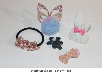 Elastics And Stilettos On A White Background. Baby Hair Ornaments. Girl Accessories Near The Casket. Hairpins, Earrings, Rings Are The Treasures Of A Little Girl. Baby Jewelry