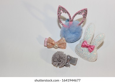 Elastics And Stilettos On A White Background. Baby Hair Ornaments. Girl Accessories Near The Casket. Hairpins, Earrings, Rings Are The Treasures Of A Little Girl. Baby Jewelry