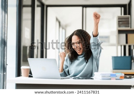 elated African American university student, possibly celebrating a successful moment in her MBA project, holding a tablet and a pen aloft.