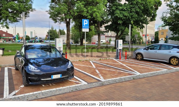 Elblag,\
Poland - July 20, 2021: A static shot of a solid black Tesla Model\
3 dual motor long range awd charging at the ENERGA (Orlen group) AC\
charging station in a sunny summer evening\
day