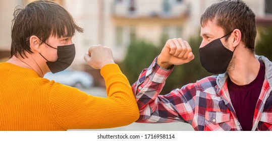 Elbow Bump. Friends Medical Mask. People Wear Face Mask Outside. Friends Bump Elbows Outdoors. Coronavirus Epidemic. Friends In Protective Medical Mask On His Face Greet Their Elbows In A Quarantine.