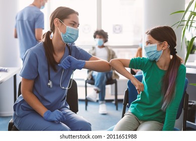 Elbow Bump Greeting. Teen Girl In Medical Mask Bumping Elbows Meeting Nurse Doctor In Hospital Indoor. Social Distancing And Keeping Safe Distance For Covid-19 Protection Concept