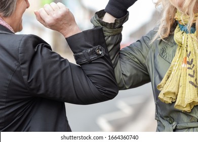 Elbow Bump. New Novel Greeting To Avoid The Spread Of Coronavirus. Two Women Friends Meet In A British Street And Instead Of Greeting With A Hug Or Handshake, They Bump Elbows Instead.