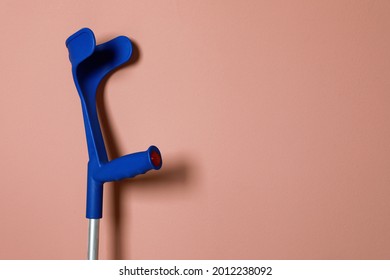 Elbow crutch on pale pink background. Space for text