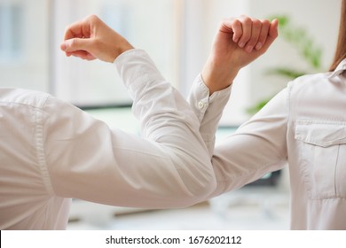 Elbow greeting to avoid the spread of coronavirus (COVID-19). Man and woman meet in an office with bare hands. Instead of greeting with a hug or handshake, they bump elbows instead. - Powered by Shutterstock