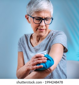 Elbow Pain Treatment. Senior Woman Holding An Ice Bag Compress On A Painful Elbow 