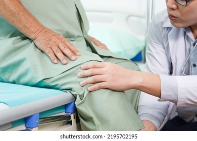 Elder Asian Man Sitting On The Bed And Talking To Doctor About His Physical Injuries At His Knees, Elderly Asian Man Having A Consulting With Professional Physical Therapist Or Orthopedic Doctor.