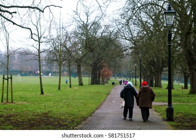 Elder Couple Walking Away In A Green Park