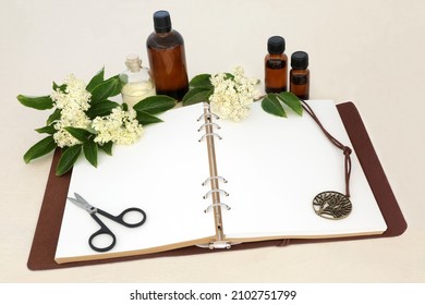 Elder flower herb flowers used in herbal plant medicine and aromatherapy with notebook, essential oil bottles. Remedy to heal colds, flu, bronchitis, swollen sinuses. Natural health care concept. - Shutterstock ID 2102751799