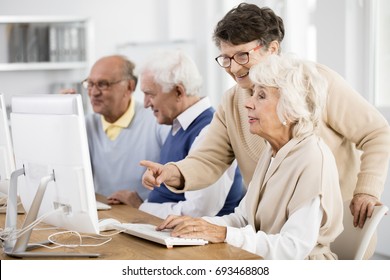 Elder lady with glasses helping her friend with computer issue - Powered by Shutterstock