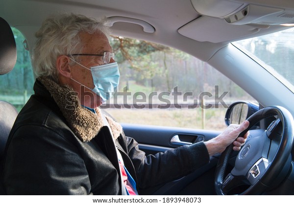 Elder man with\
facemask in car on the\
road