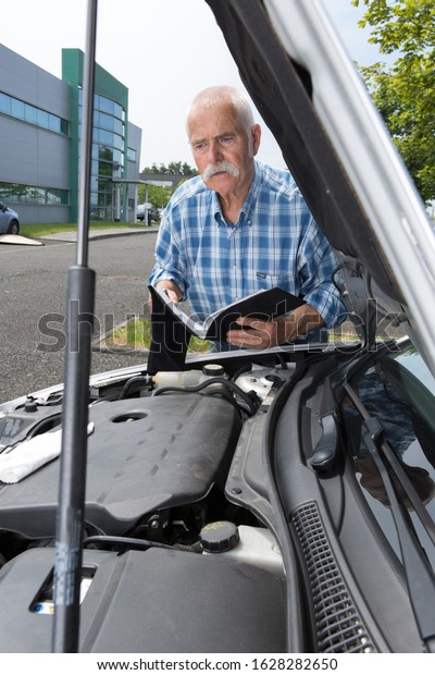 elder man servicing his car\
at home
