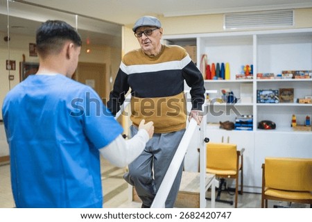Elder man using parallel bars for physical therapy, assisted by a male nurse, focusing on rehabilitation and mobility in a care facility