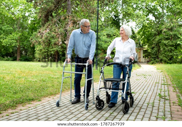 Elder man\
and a elder woman strolling using\
walkers