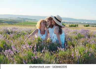 Elder Mother, Adult Daughter And Grandchild Posing In The Field Together. Mature Parent Hugging The Daughter In Countryside. Three Female People Rest Outdoor Female Generation