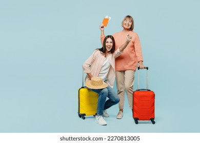 Elder parent mom with young daughter two women in casual clothes hold passport ticket valise isolated on plain blue background Tourist travel abroad in free time rest getaway. Air flight trip concept