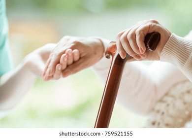 Elder person using wooden walking cane during rehabilitation in friendly hospital - Powered by Shutterstock