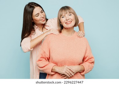 Elder retired tired parent mom with young adult daughter two women together wear casual clothes massaging mother's shoulders make to relax isolated on plain blue cyan background. Family day concept - Shutterstock ID 2296227447