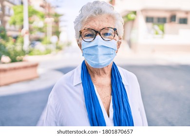 Elder senior woman with grey hair wearing coronavirus safety mask outdoors - Powered by Shutterstock