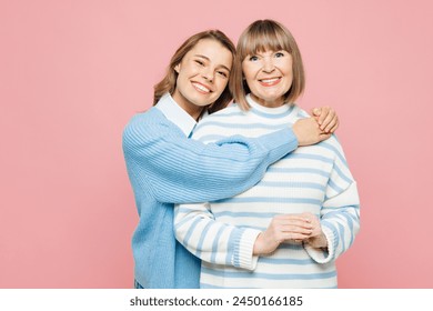 Elder smiling happy parent mom 50s years old with young adult daughter two women together wear blue casual clothes hug looking camera isolated on plain pastel light pink background. Family day concept - Powered by Shutterstock