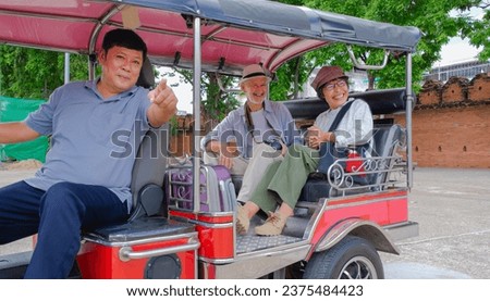Elder tourists enjoy tuktuk ride in Thailand. They bargain and use tablet as guide for driver's best service. Tourist have big fun to take a trip on tuktuk.