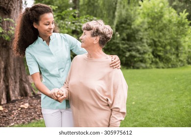Elder woman and caregiver walking in the park - Powered by Shutterstock