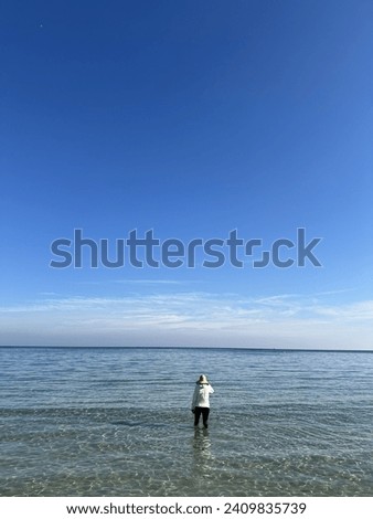 Similar – a woman looks at the sea. rear view, blurred