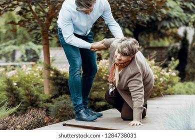 Elder Woman Getting Up With The Help Of Her Son