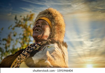 elder woman from southern Africa dressed in a traditional costume with a hat and cow hide in a village in the rural area - Powered by Shutterstock