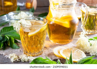 Elderberry flowers and lemon drink. Refreshing healthy summer juice. Glass of elderflower lemonade on wooden rustic board. Alternative medicine and therapy.