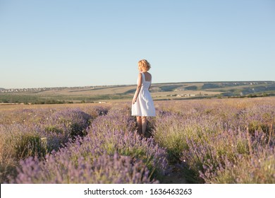 Elderly 50s woman dressed white sundress posing in the nature in the yellow field in harmony relaxation. Female enjoy meadow for tranquility and freedom from city life.  
