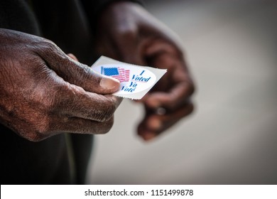 An elderly African American man holds his “I voted” sticker after he cast his ballot in Washington, DC.