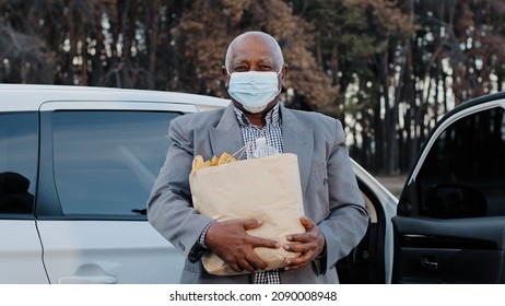 Elderly African American Man In Protective Medical Mask In Street Parking Bought Groceries In Fruit Shop Senior Male Stand Near Automobile Holds Package Products Outdoors Quarantine Measures Pandemic