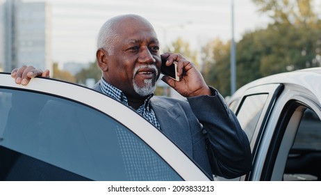 Elderly african american man talking on mobile phone walks up to car sits down in front passenger seat answers call using smartphone mature businessman discussing business conversation on telephone