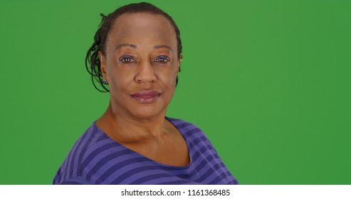 An elderly African American woman poses for a portrait on green screen