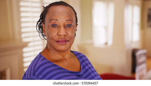 An elderly African American woman poses for a portrait in her house