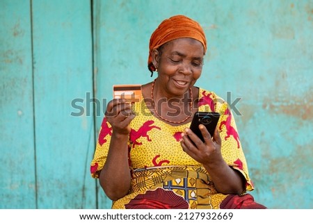 elderly african woman holding her phone and credit card