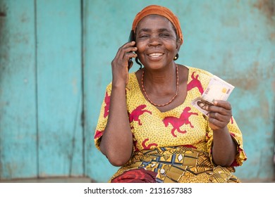 elderly african woman holding some money, making phone call